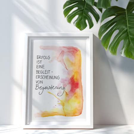 Ein Kunstdruck mit Aquarellhintergrund in Gelb-, Orange- und Rottönen. In der Mitte steht der Text „Erfolg ist eine Randerscheinung von Begeisterung“ in Schreibschrift.