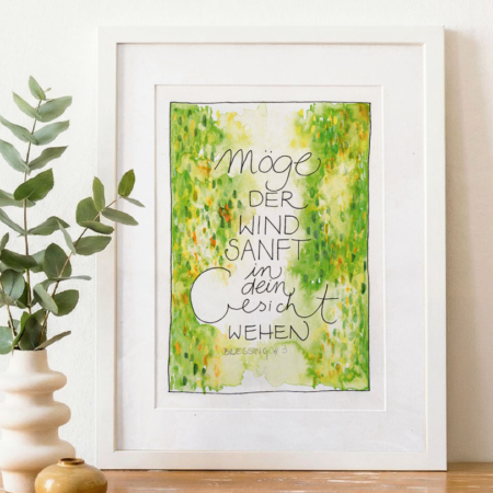 „Möge der Wind sanft in dein Gesicht wehen – Blessing #3“. Der Druck steht auf einem Holztisch neben einer weißen Vase mit Eukalyptuszweigen und einer kleinen Keramikschale. Helles, natürliches Licht, ruhige, warme Wohnatmosphäre.