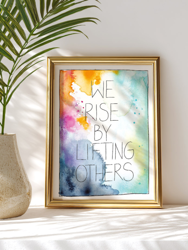 Ein Kunstdruck in Din A4 mit Aquarellhintergrund in Gelb-, Blau-, Grün- und Pinktönen. In der Mitte steht der Text „We rise by lifting others“ in Schreibschrift.
