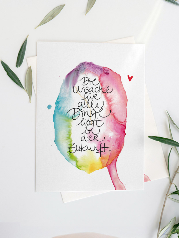 Postkarte eines Aquarells in lebendigen, ineinanderfließenden Farben – von kühlem Blau und Grün bis zu warmem Rot, Pink und Gelb. Im Zentrum steht in geschwungener, handgeschriebener Schrift der Satz: Die Ursache für alle Dinge liegt in der Zukunft.